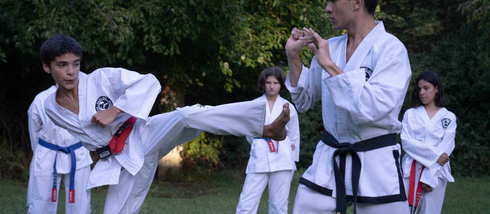 Grupo de deportistas juveniles con distintos cinturones entrenando juntos al aire libre
