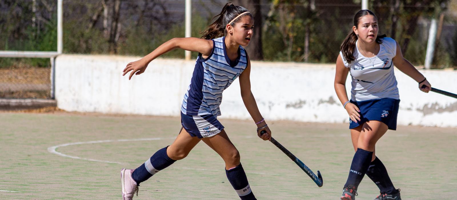 Jugadoras juveniles de hockey en cancha, en plena disputa
